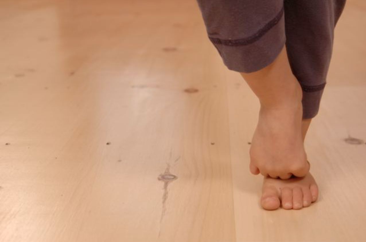 child standing barefoot on a wooden floor